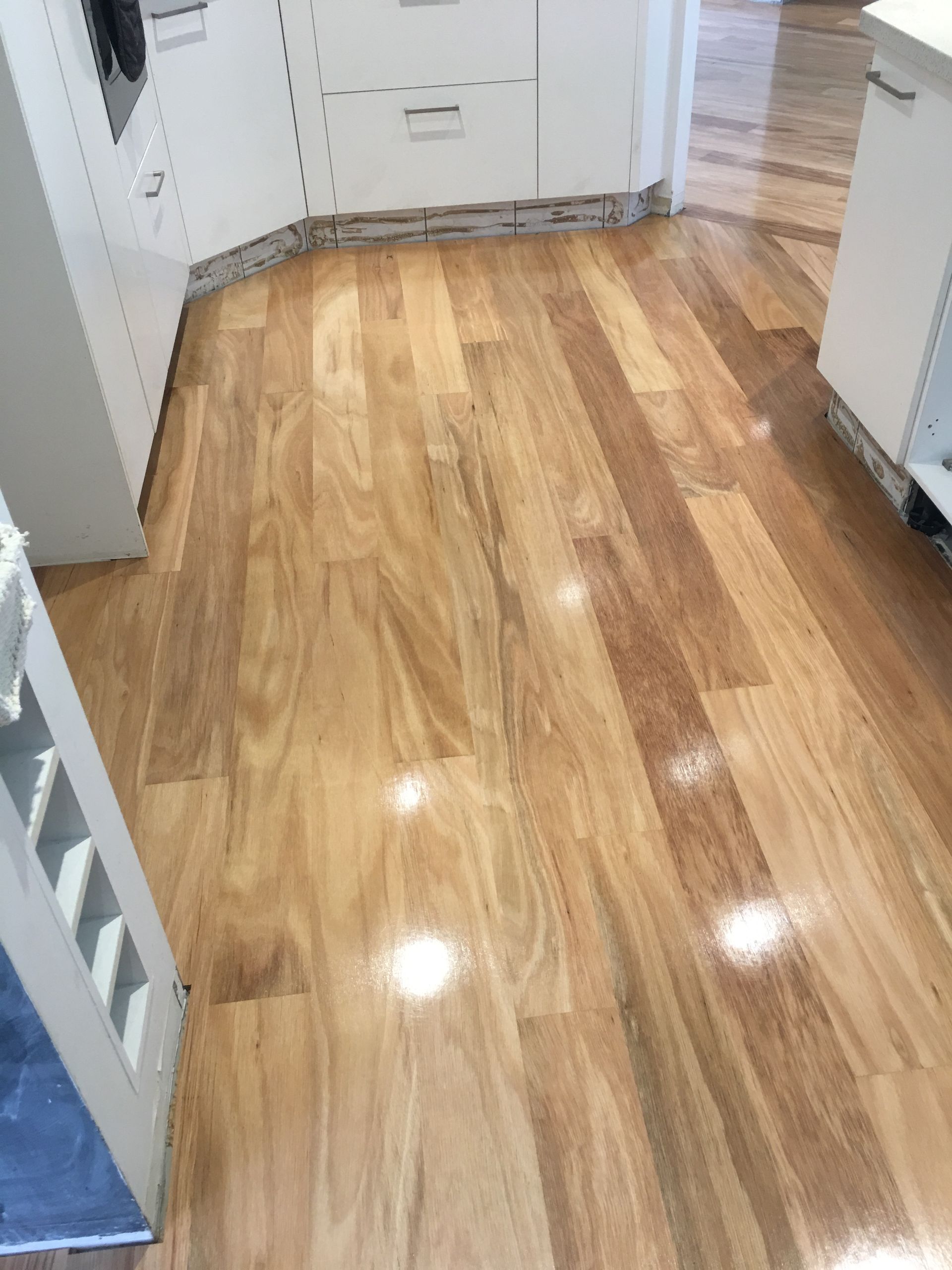 A Kitchen With a Wooden Floor and White Cabinets — Timberfection Queensland in Yatala, QLD