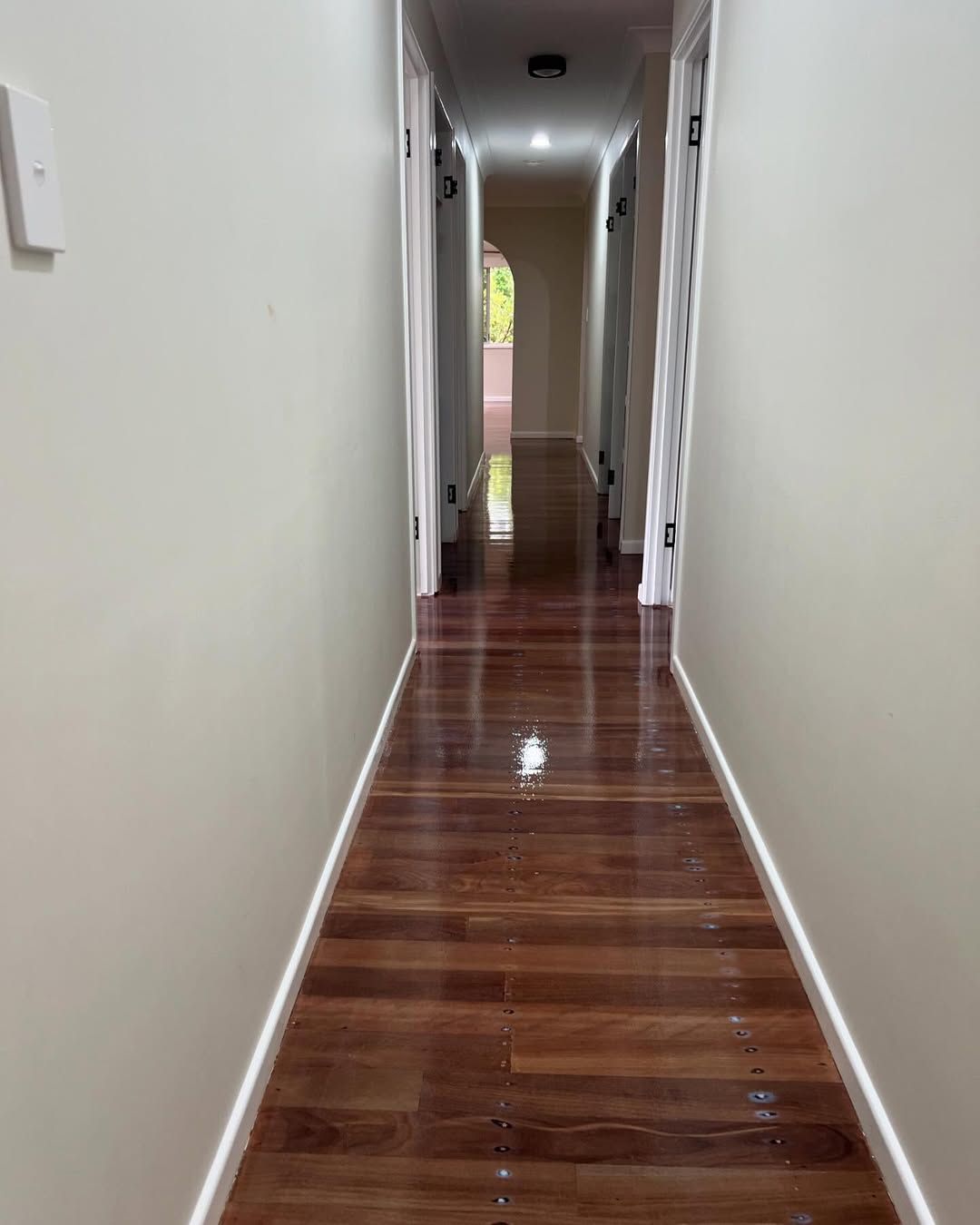 A Long Hallway With Hardwood Floors and White Walls — Timberfection Queensland in Yatala, QLD