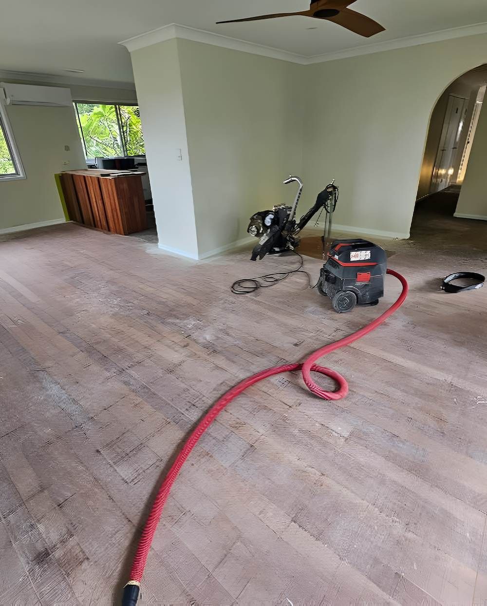 A Vacuum Cleaner is Sitting on a Wooden Floor in a Living Room — Timberfection Queensland in Yatala, QLD