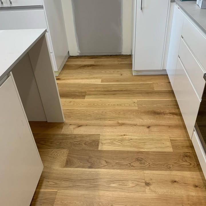 A Kitchen With Hardwood Floors and White Cabinets — Timberfection Queensland in Yatala, QLD