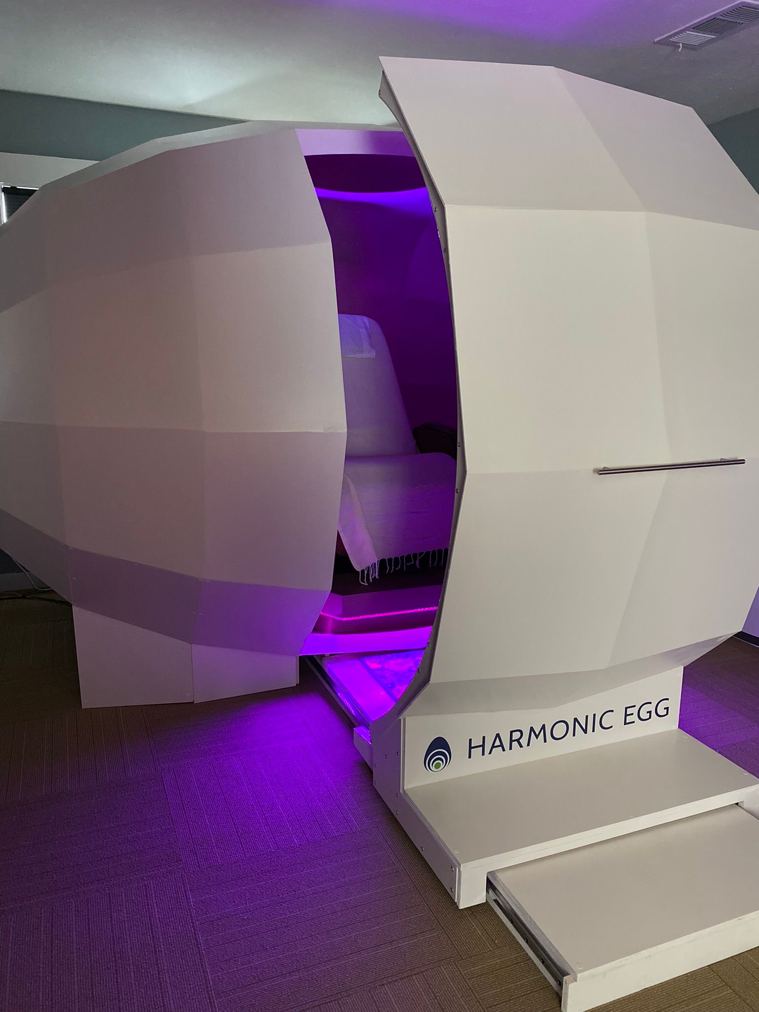 A purple light is shining on a white object in a room.