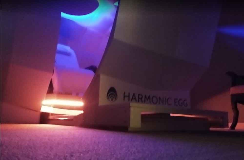 A harmonic egg is lit up in a dark room