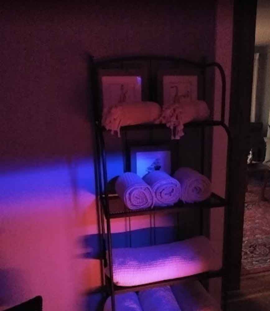 A shelf with towels on it is lit up with purple lights.