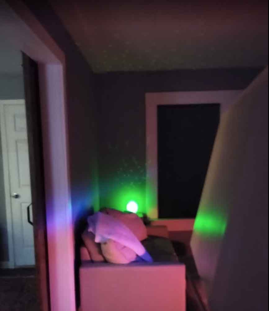 A living room with a couch and a green light on the wall.