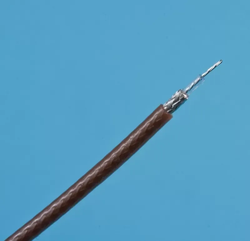 A close-up of a brown, shielded coaxial cable with a stripped end showing the inner silver wire against a blue background.