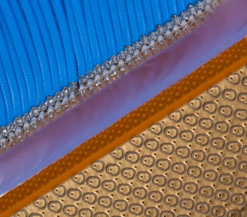 A close-up view of a blue, ribbed fabric, a thin rhinestone trim, a pink border, and a tan, dimpled textured surface.