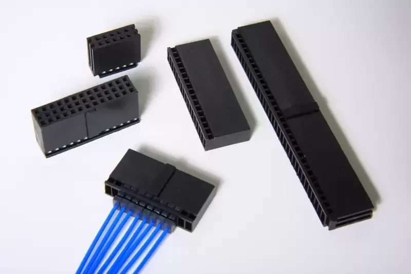 Black rectangular electrical wire connectors, one with blue cables attached, arranged on a white background.