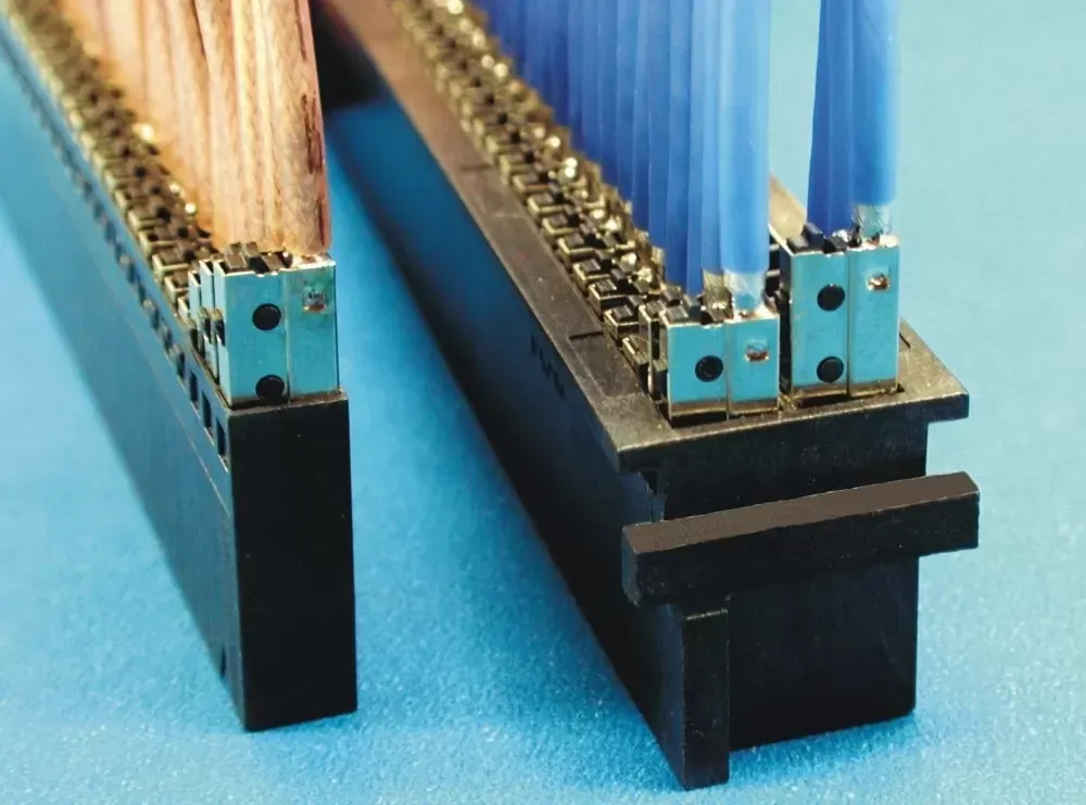 Two black electronic terminal blocks with rows of metal contacts, one holding brown wires and the other blue wires.