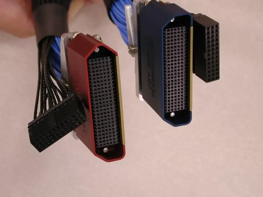 Two high-density, multi-pin electrical connectors in red and blue, each attached to bundled black and blue cables.