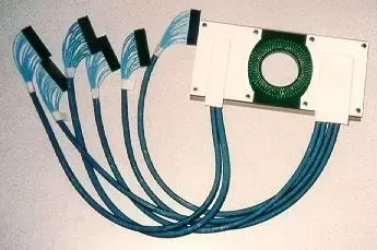 A white rectangular frame with a circular green circuit board center, connected to five blue wire bundles with black ends.