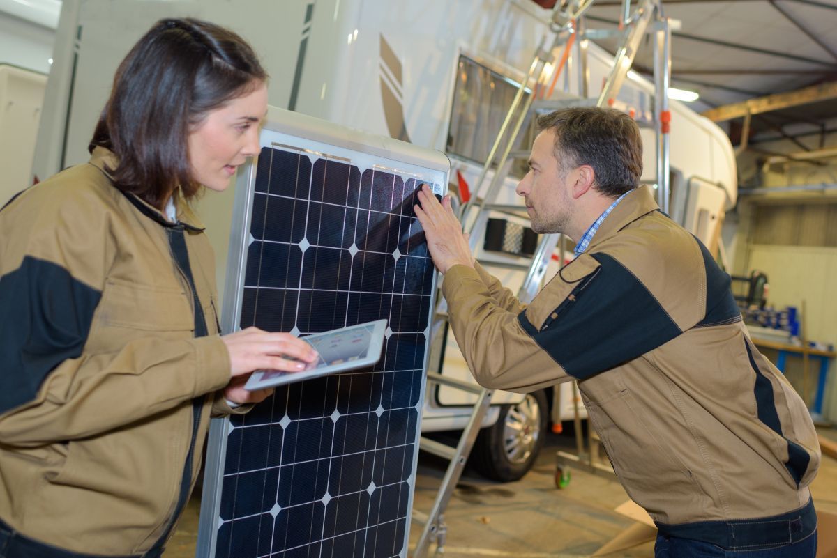 a man and a woman are working on a solar panel