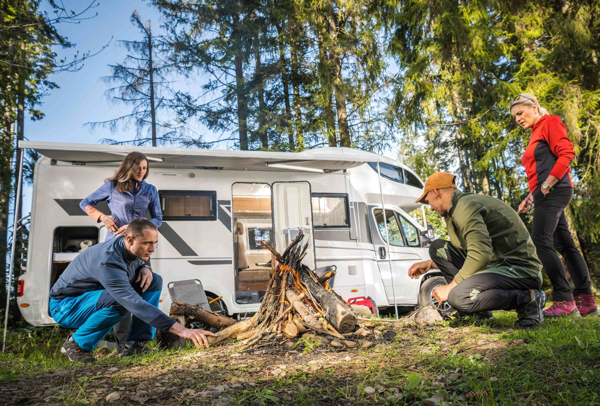 a group of people are sitting around a campfire in front of a rv