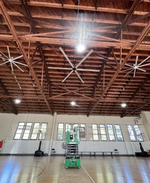 A ceiling fan is hanging from the ceiling of a gym.