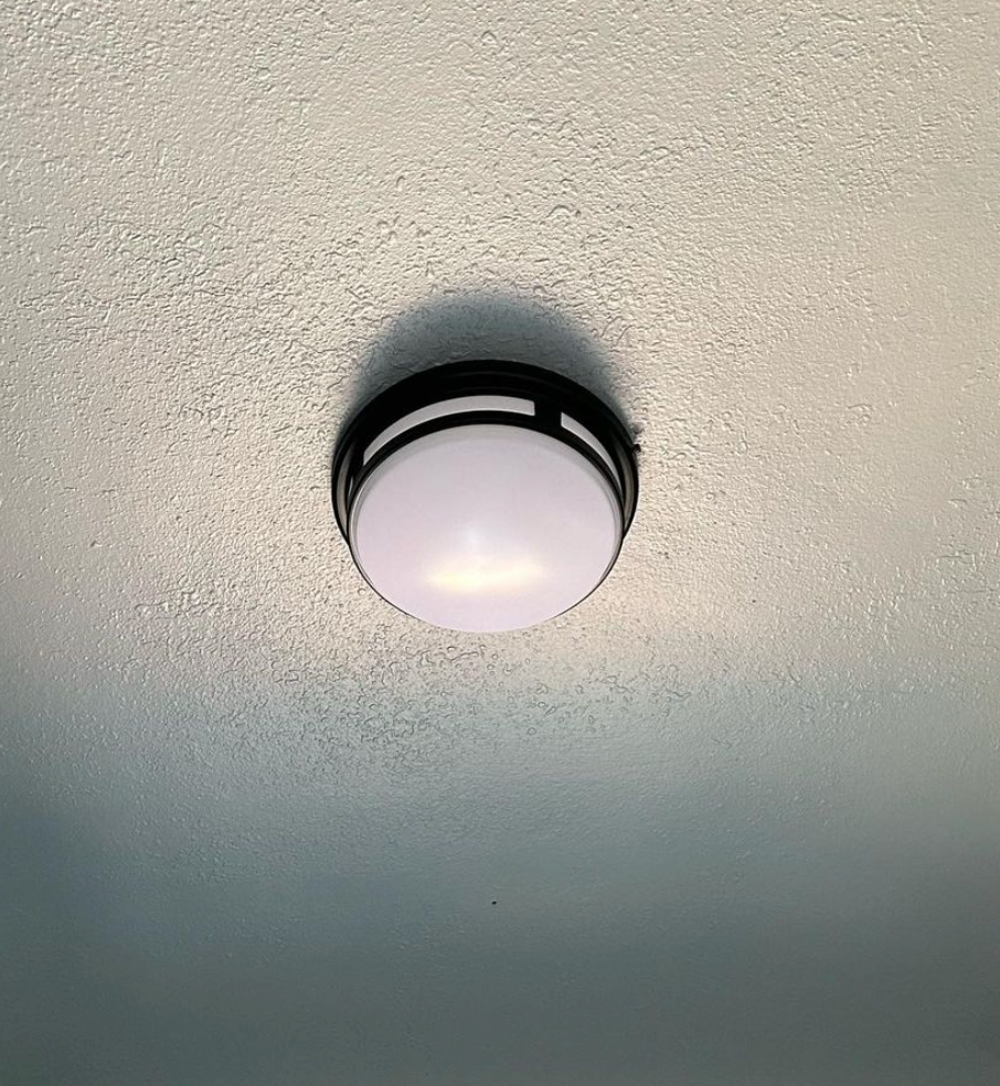 A white light is hanging from the ceiling of a room.