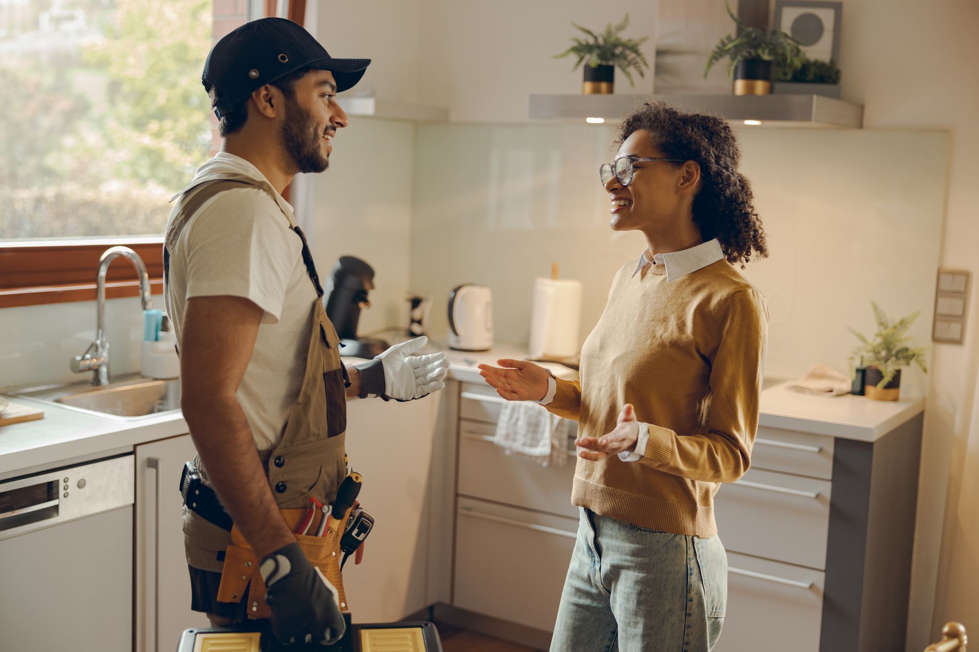 A man and a woman are standing in a kitchen talking to each other.