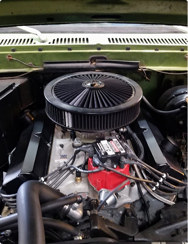 Classic car engine bay with a large black air filter and red engine block. | Hudson Automotive
