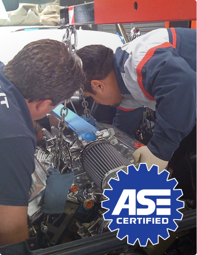 Two mechanics inspecting an engine in a garage with an ASE Certified logo | Hudson Automotive