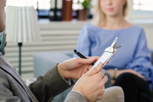 A man is holding a clipboard and talking to a woman.