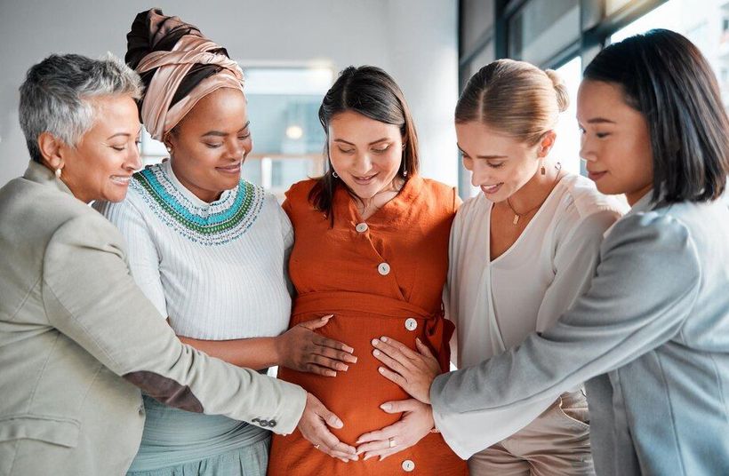 A group of women are standing around a pregnant woman.