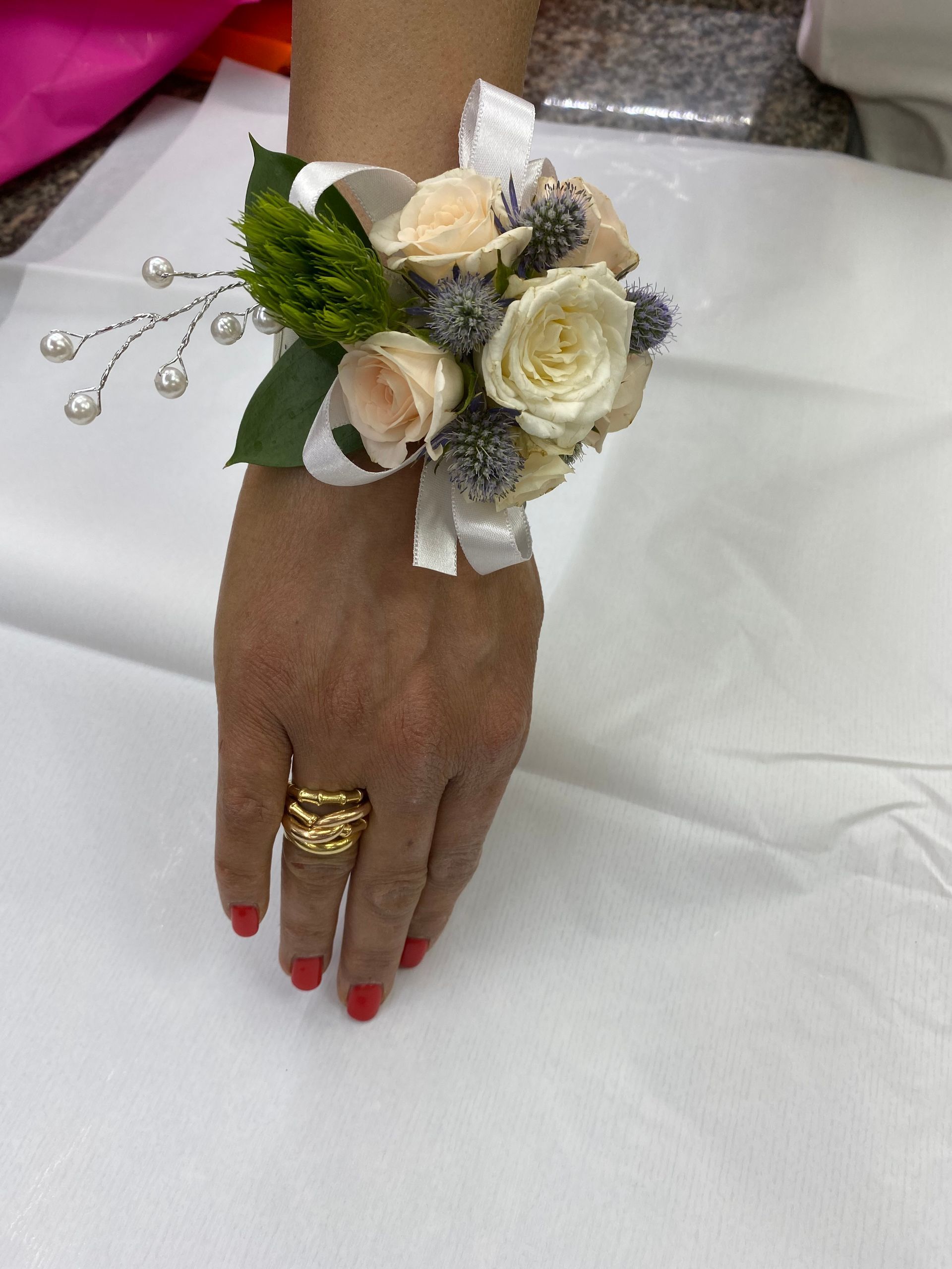 Una mano con un bouquet di rose bianche e un anello d'oro, appoggiata su una tovaglia bianca.