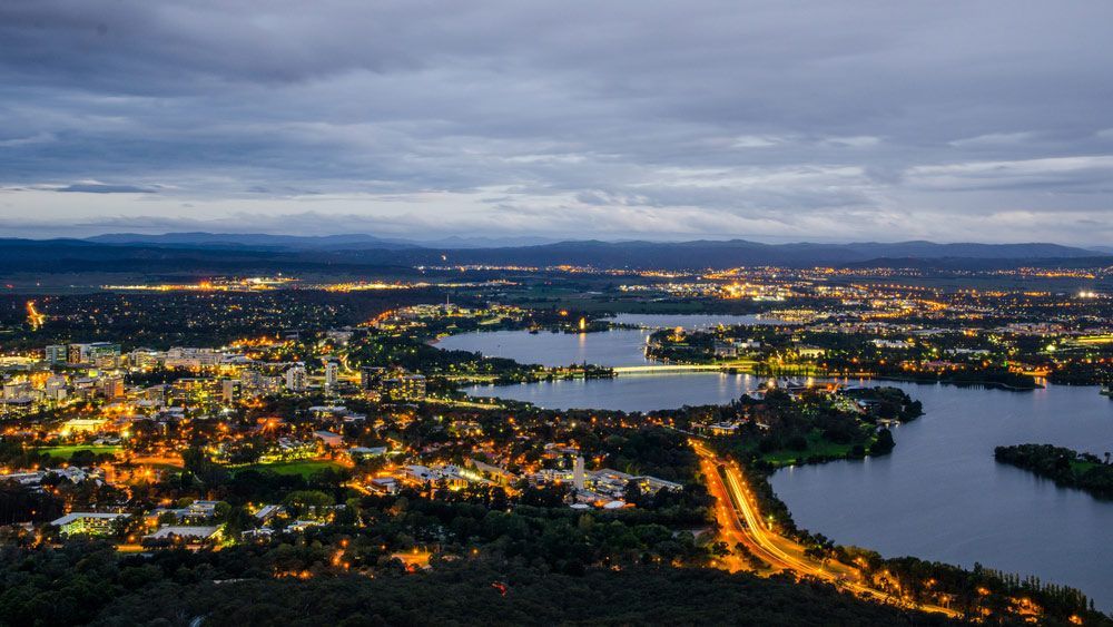 An Aerial View Of A City At Night With A Lake In The Middle — Clearspan Builders In Canberra, ACT