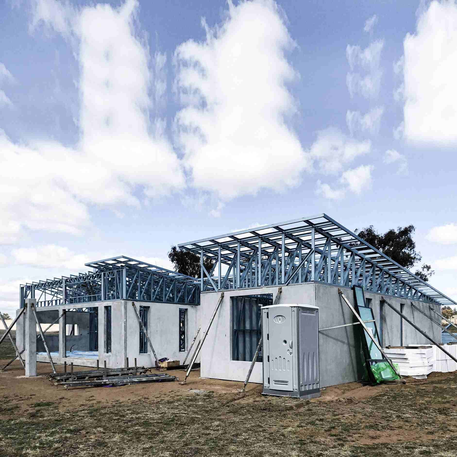 A House Is Being Built In A Field With A Blue Sky In The Background — Clearspan Builders In Queanbeyan East, NSW