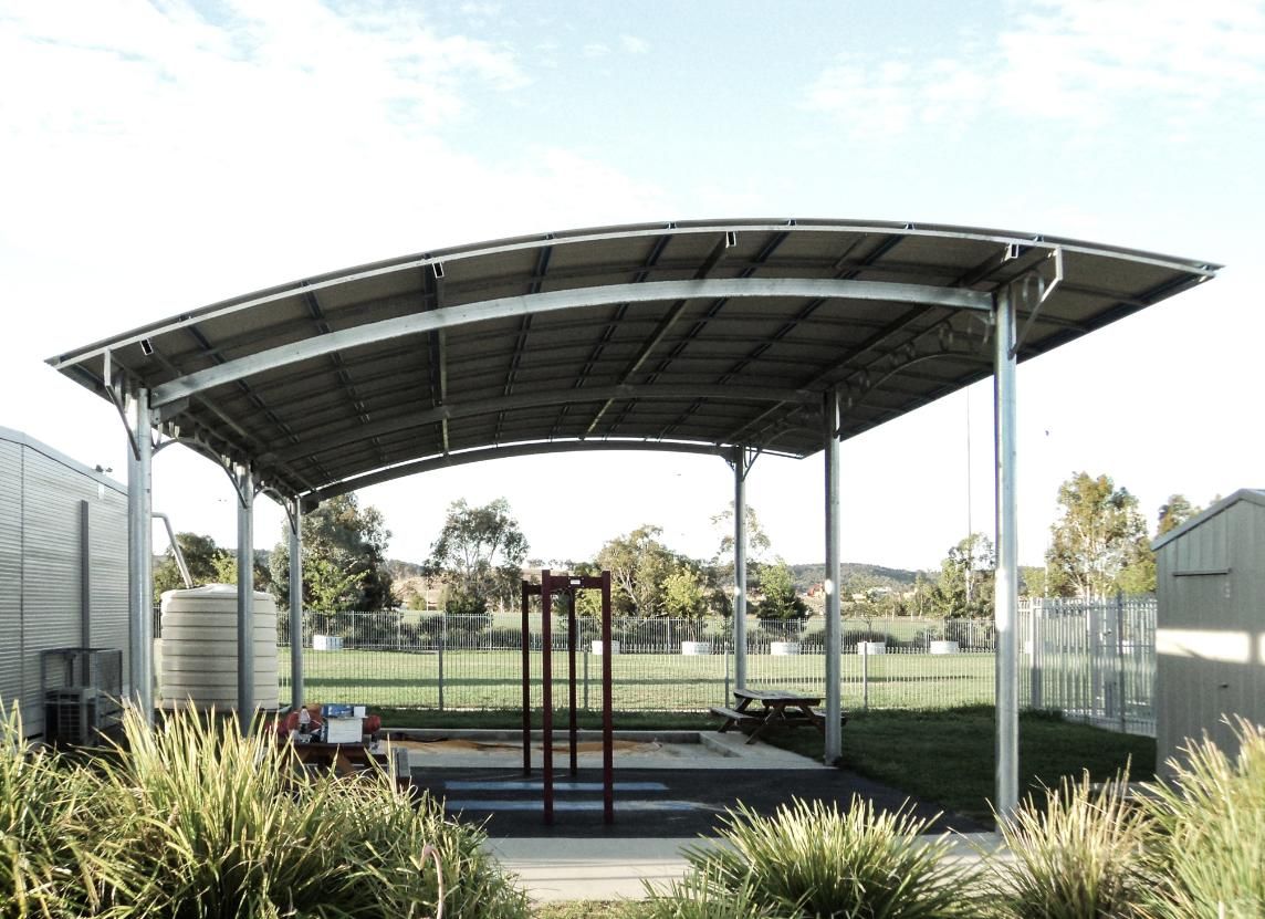 A Metal Structure with A Curved Roof in A Park — Clearspan Builders In Queanbeyan East, NSW
