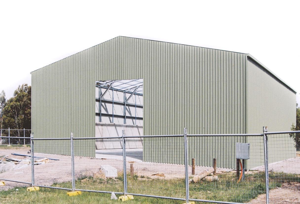 A Large Building with A Fence Around It Is Being Built — Clearspan Builders In Queanbeyan East, NSW