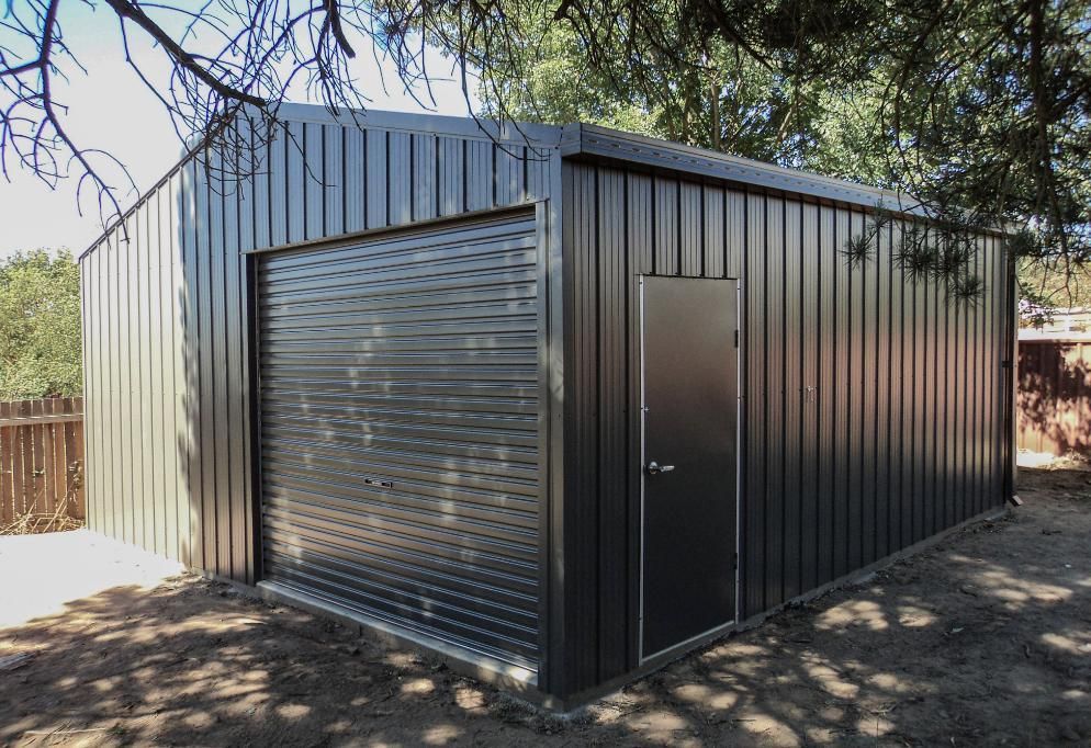 A Black Metal Garage with A Door and Roller Shutters — Clearspan Builders In Queanbeyan East, NSW