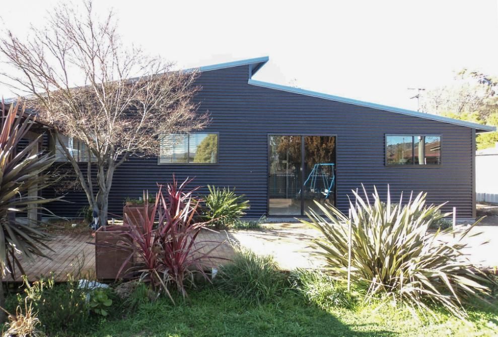 A Black House with A Lot of Windows and Trees in Front of It — Clearspan Builders In Queanbeyan East, NSW