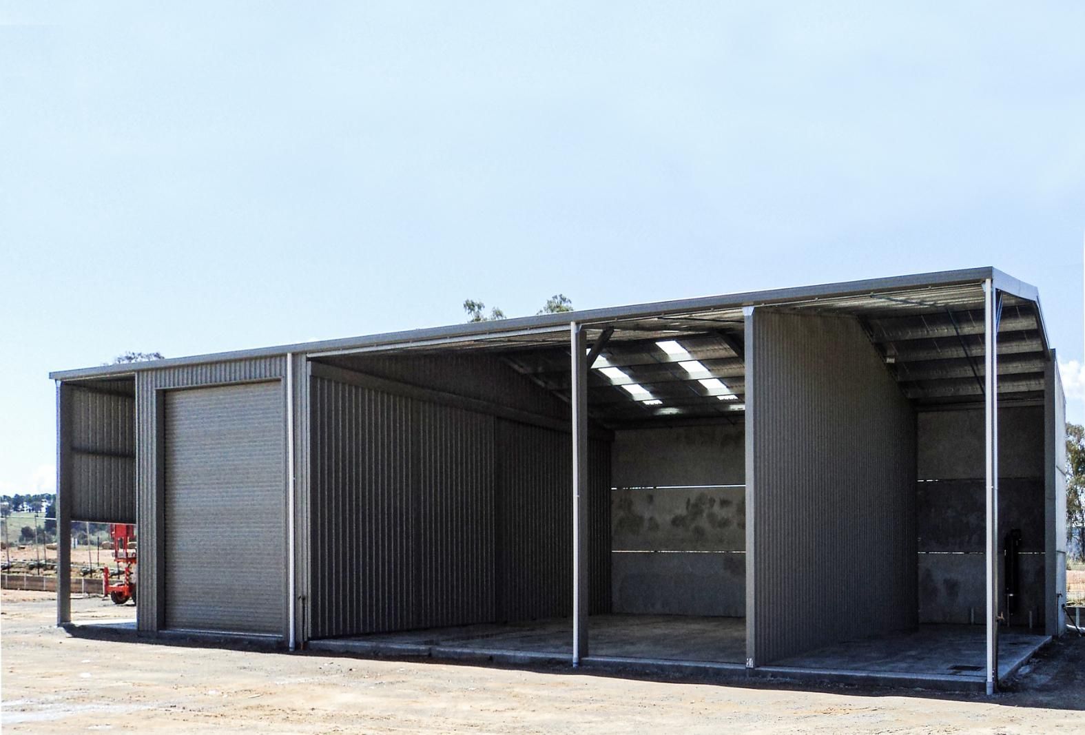 A Large Metal Building Is Sitting in The Middle of A Dirt Field — Clearspan Builders In Queanbeyan East, NSW