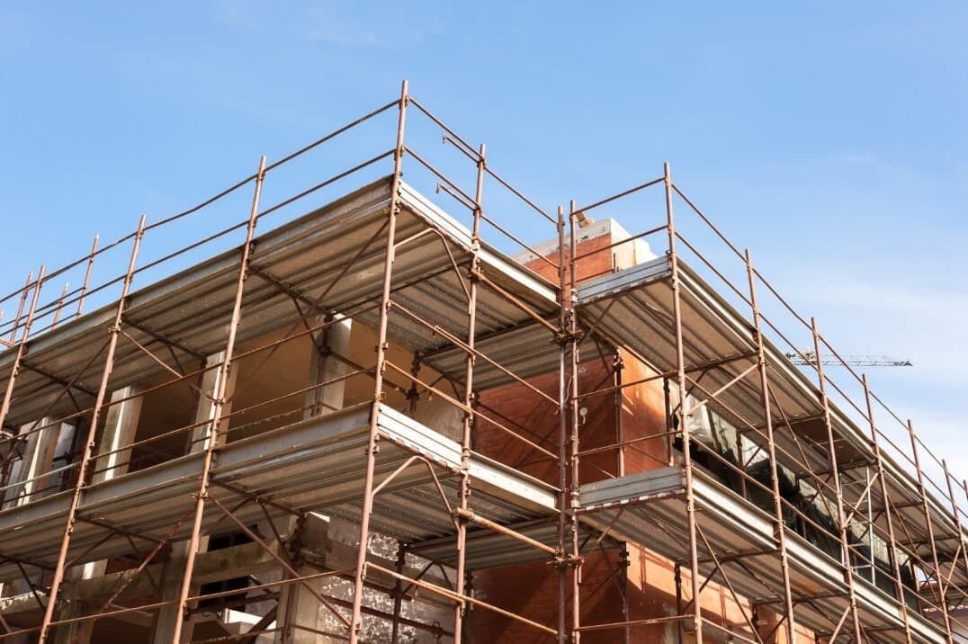 Scaffolding Surrounds the Corner of a Building Under Construction; Blue Sky Overhead — Clearspan Builders In Bungendore, NSW