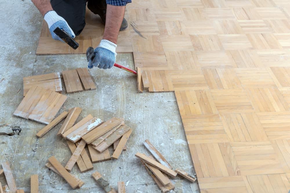 A Person Kneels, Installing Wood Parquet Flooring — Clearspan Builders In Yass, NSW