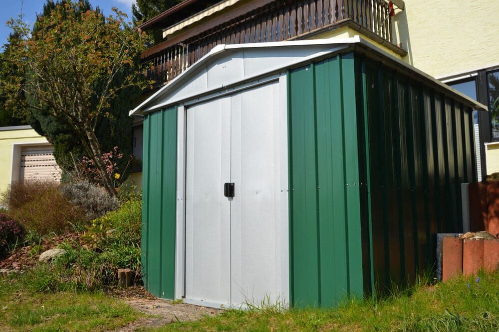 Green and Silver Metal Shed in a Backyard With a House in the Background — Clearspan Builders In Yass, NSW
