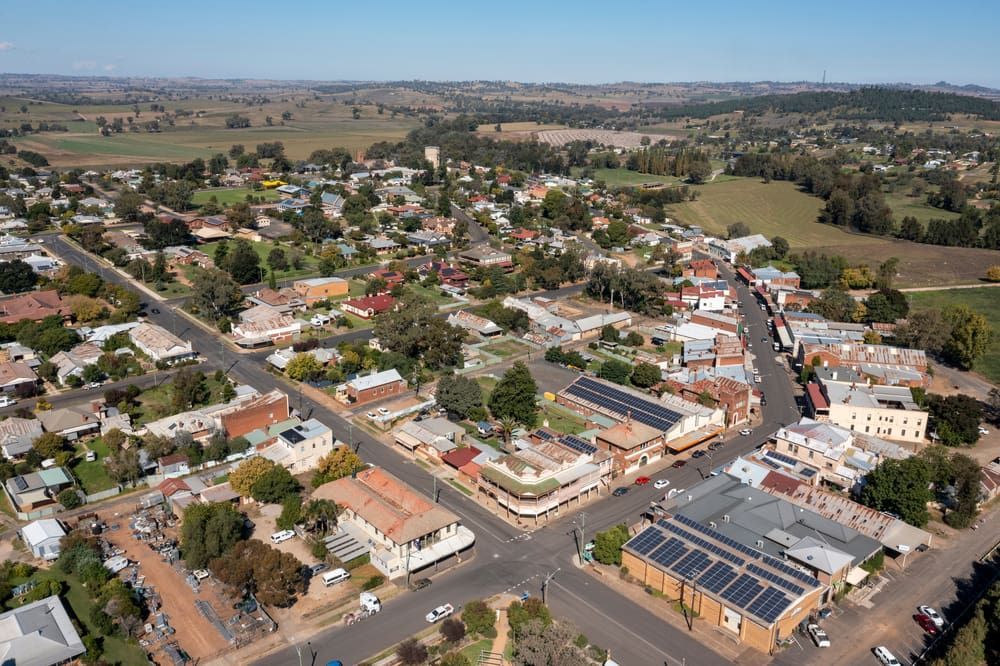 Aerial View of a Rural Town With Buildings, Trees, and Roads Under a Blue Sky — Clearspan Builders In Royalla, NSW