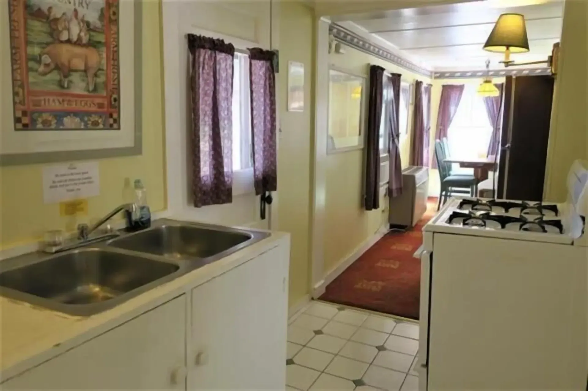 A kitchen with a sink , stove and a picture on the wall.