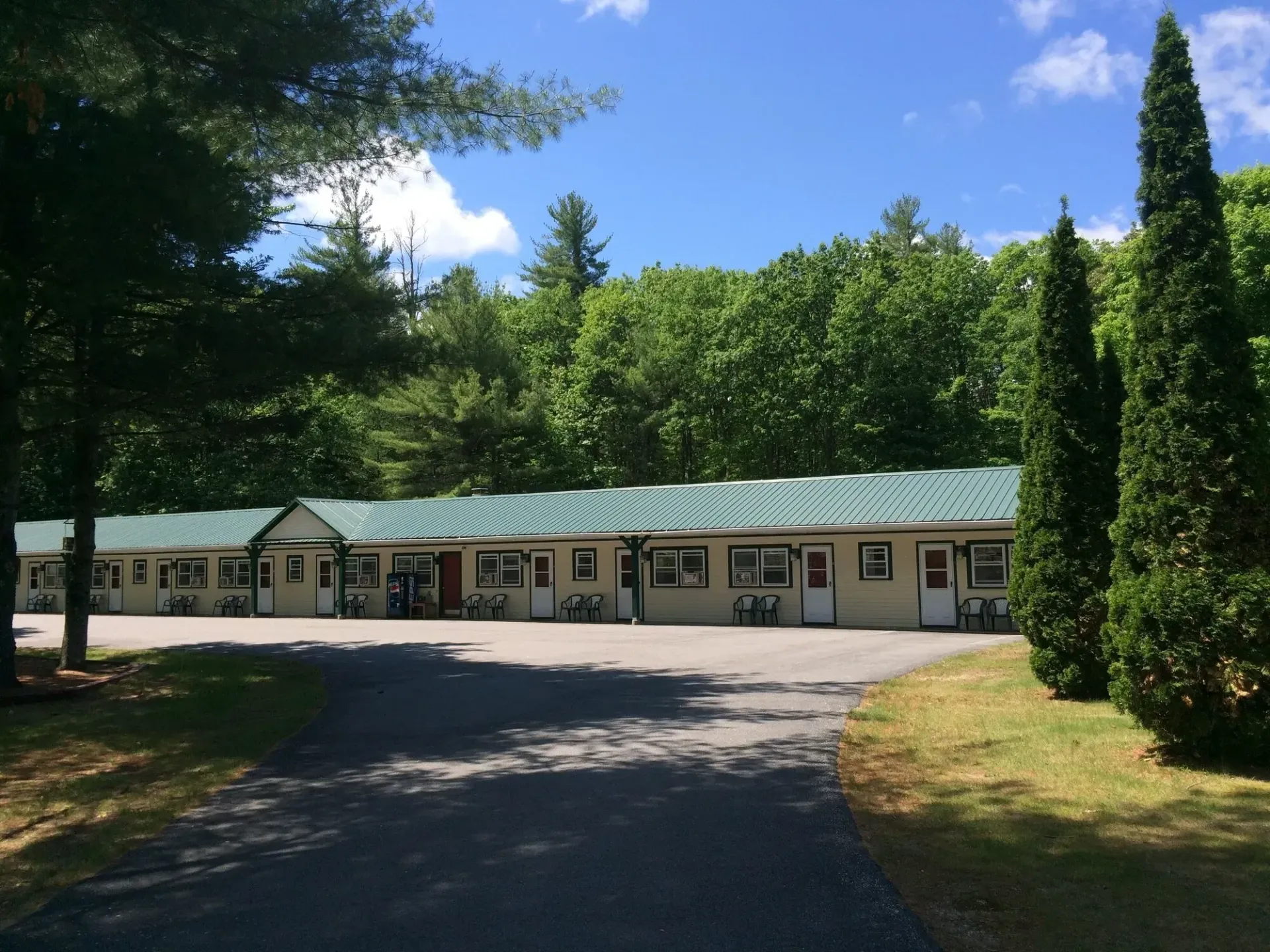 A motel with a green roof is surrounded by trees