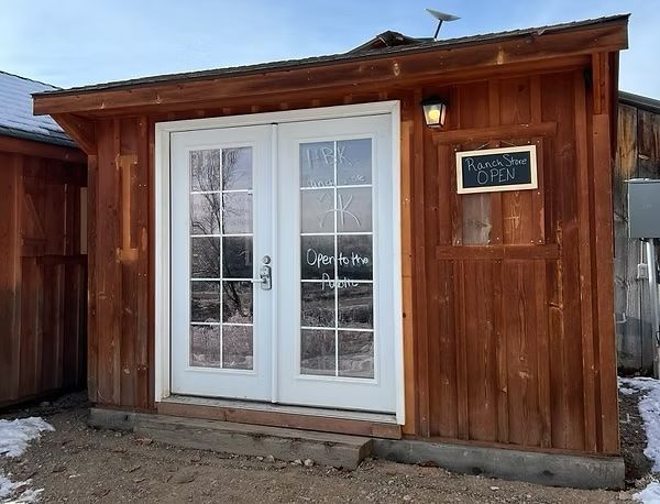 A small wooden shed with white doors and a chalkboard on the side.