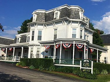 White Victorian house with porch decorated with patriotic bunting.