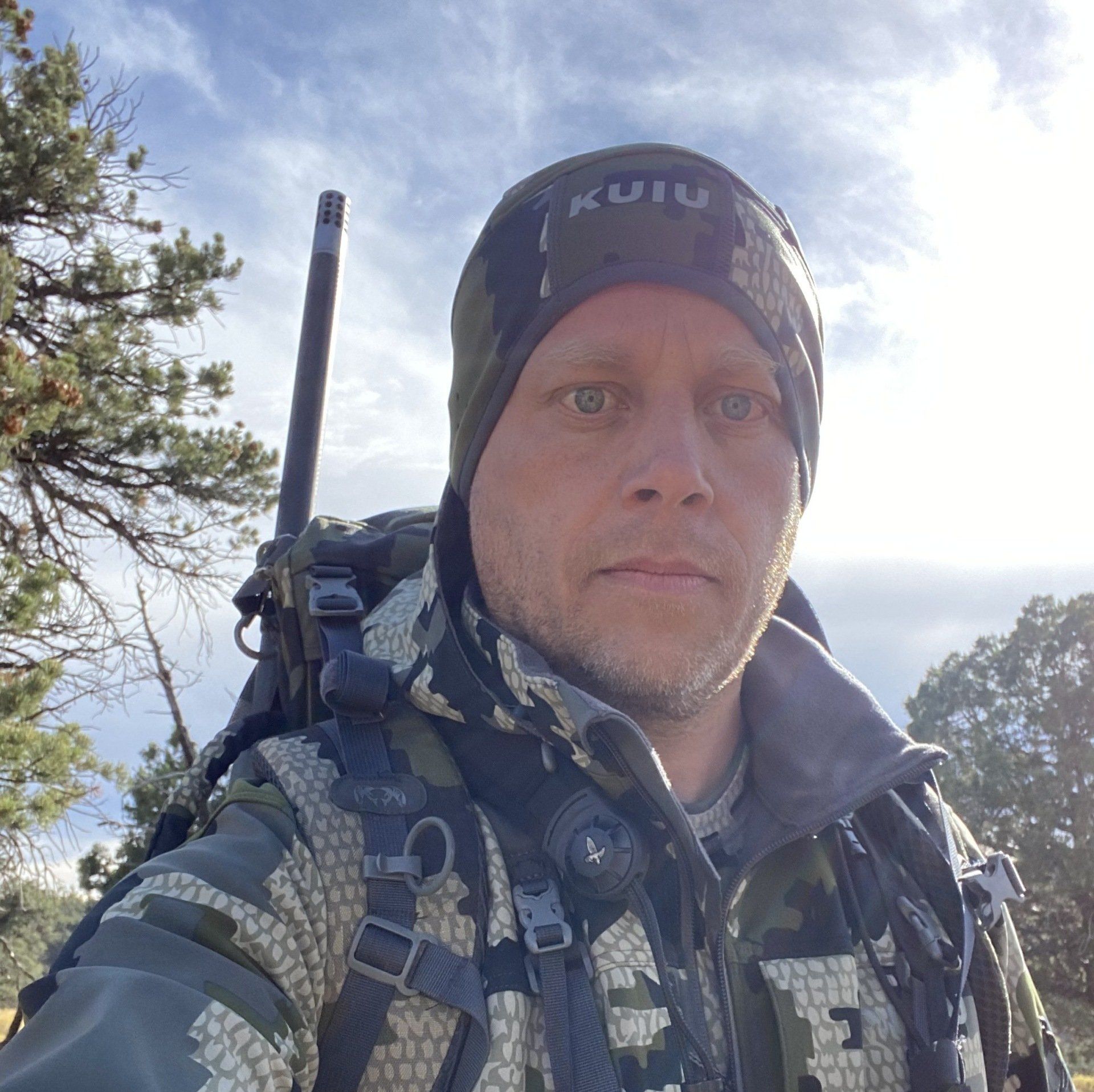 A person in camouflage gear stands outdoors.