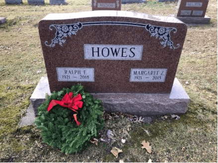 a gravestone for howes in a cemetery with a wreath on it .