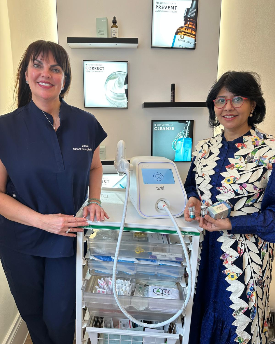 Two women are standing next to each other in front of a machine.