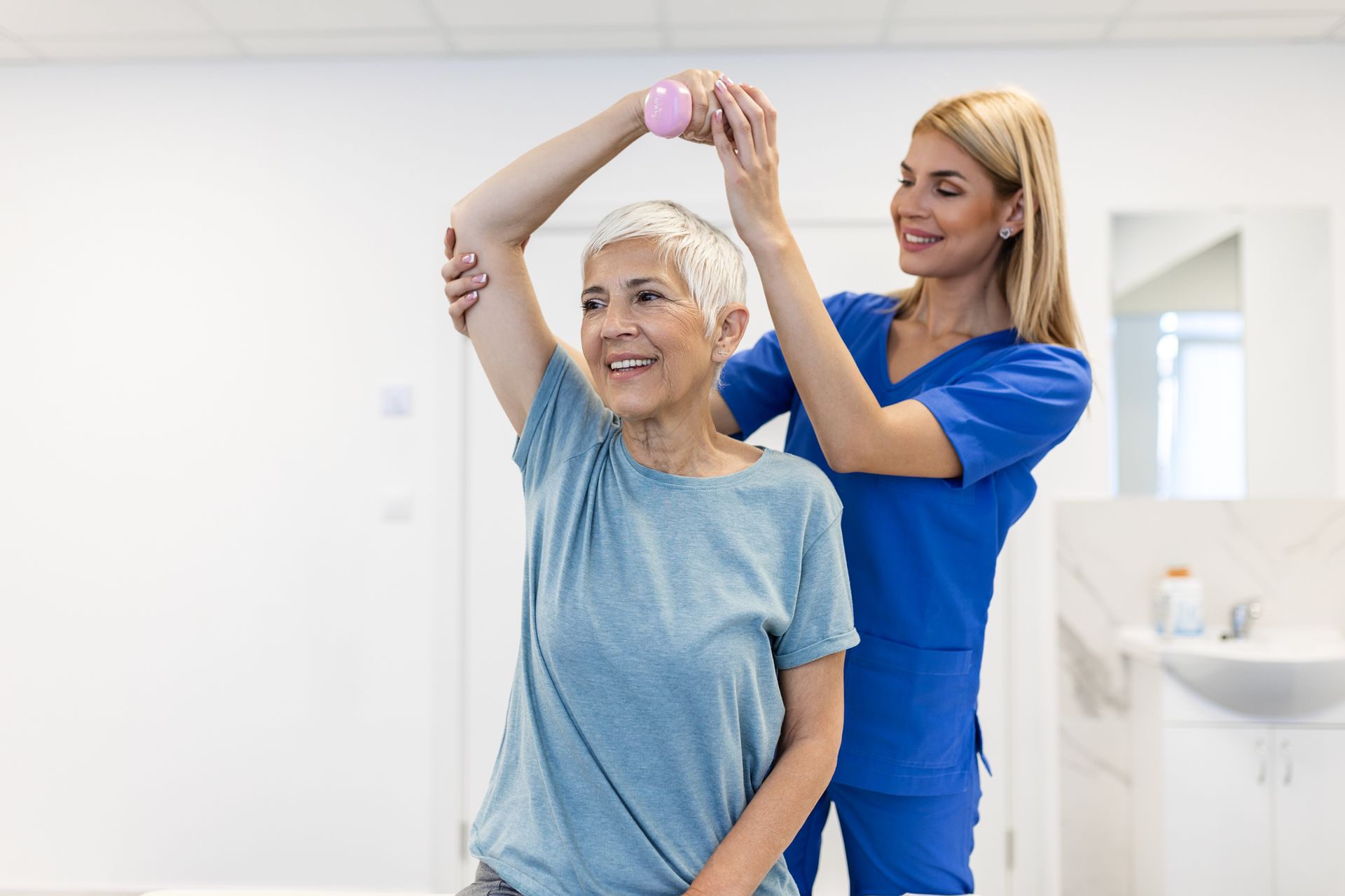 Physiotherapist helping a woman with a shoulder and arm exercise using a dumbbell for treatment.