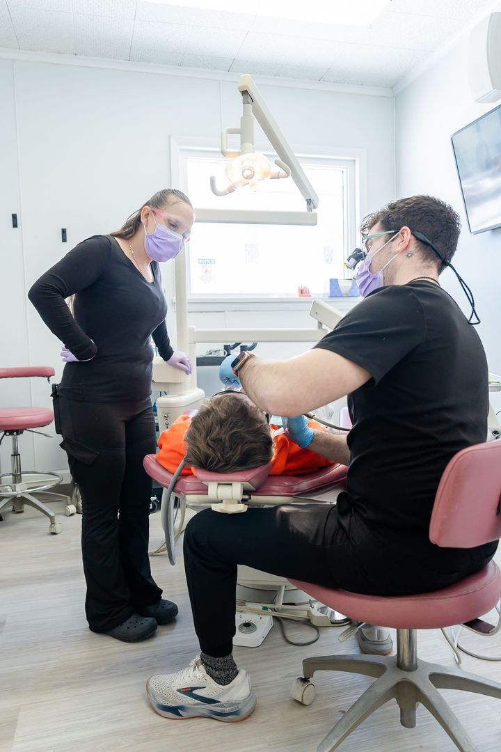 Dentist and assistant working on a patient in a dental office.