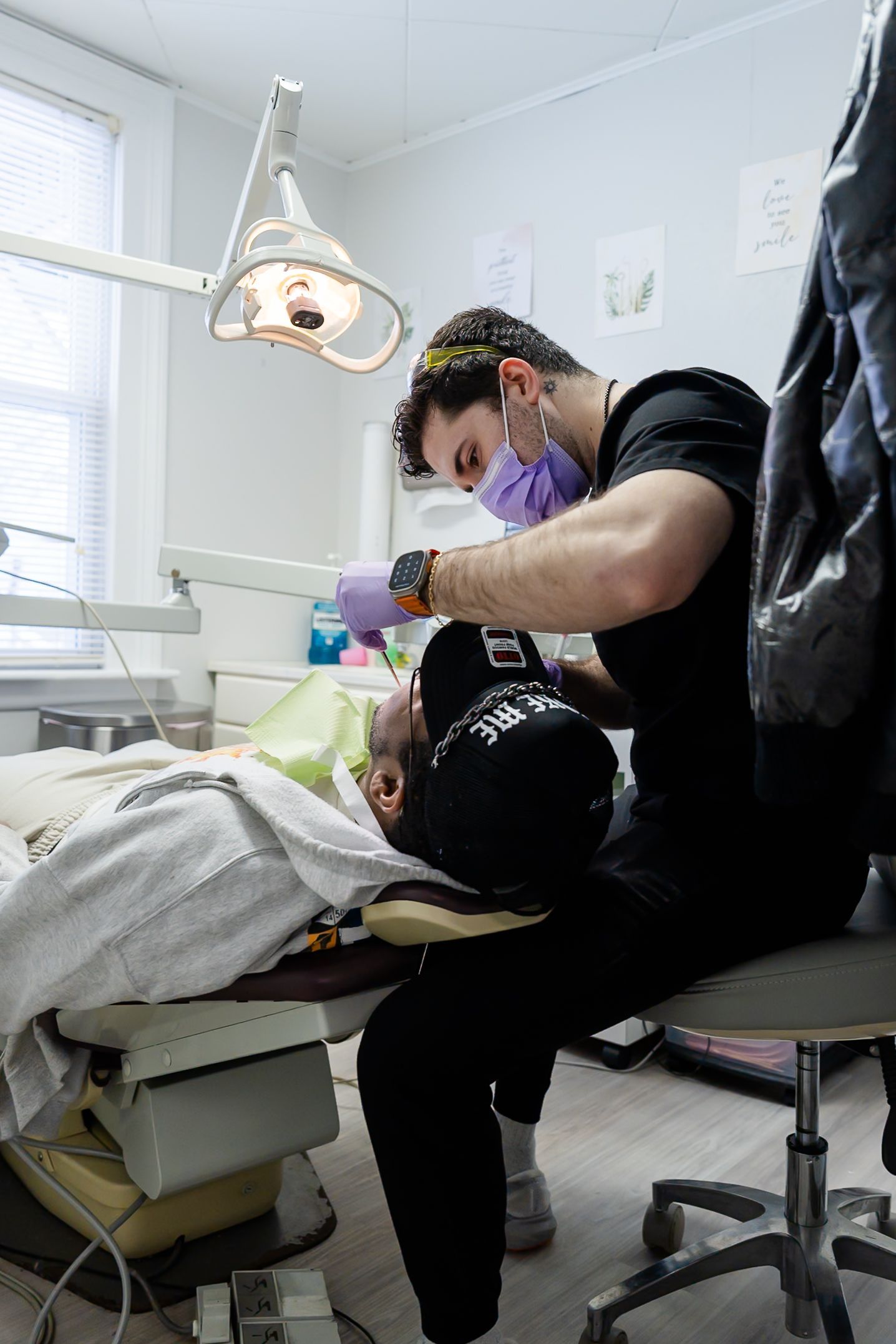 Dentist performing dental work on a patient in a bright, clinical office.
