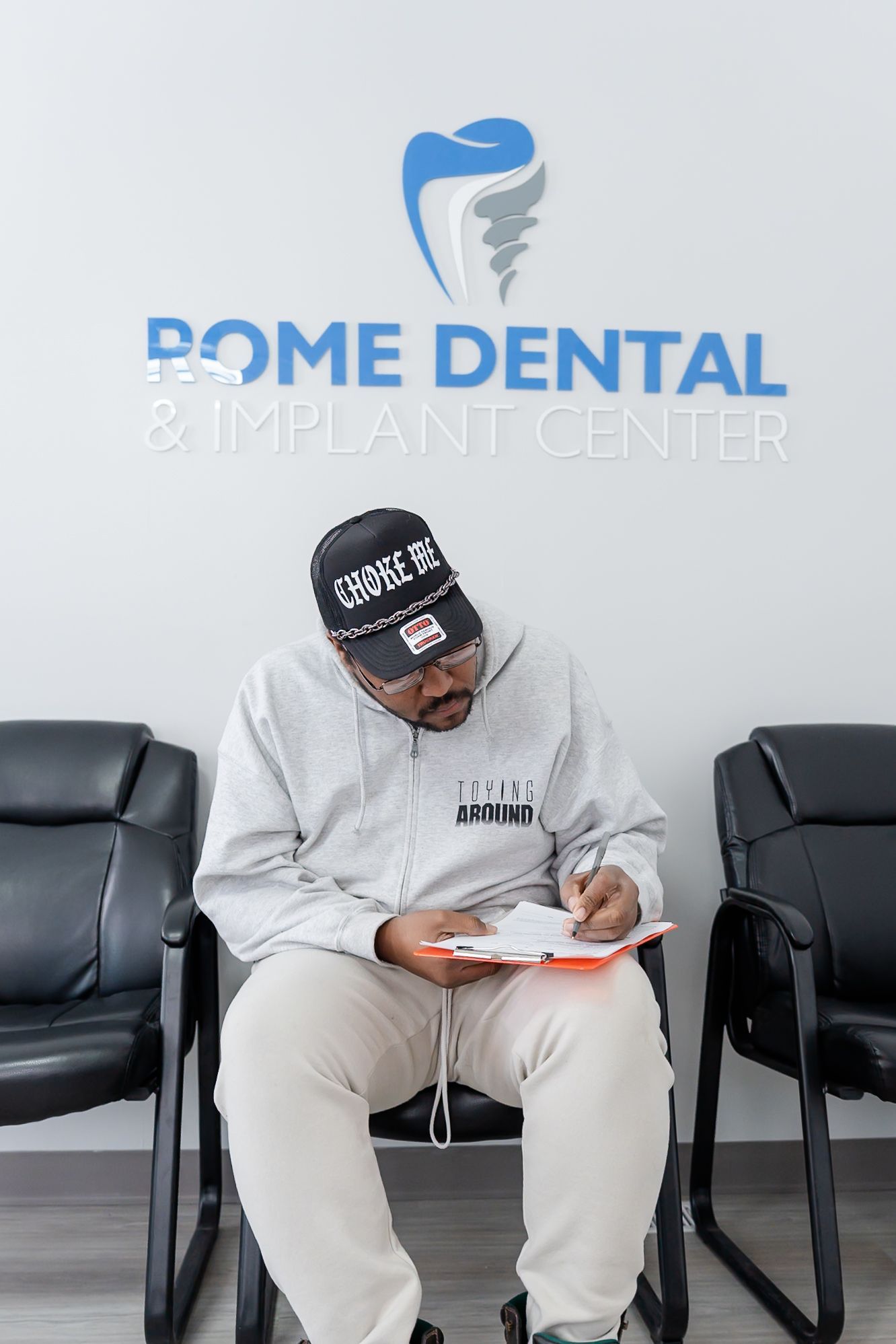Man in a waiting room filling out paperwork at Rome Dental & Implant Center.