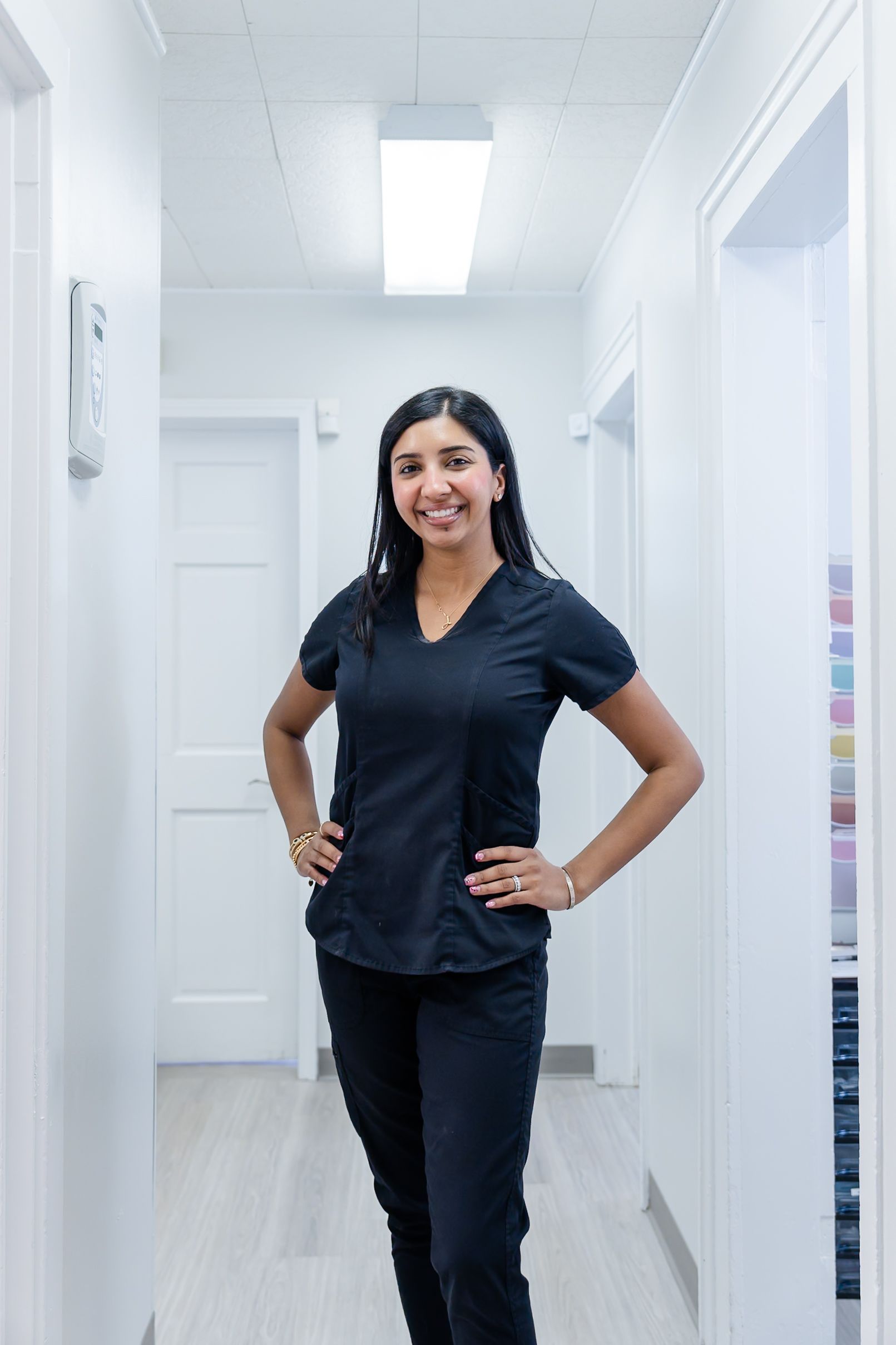 Woman in red sweater, smiling, leaning on a counter, near a window and printer.