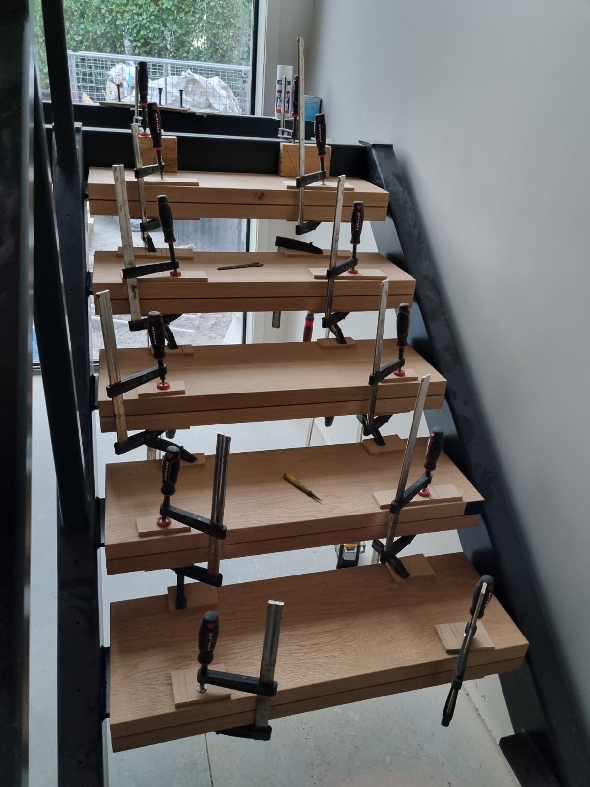 A wooden staircase is being built with clamps