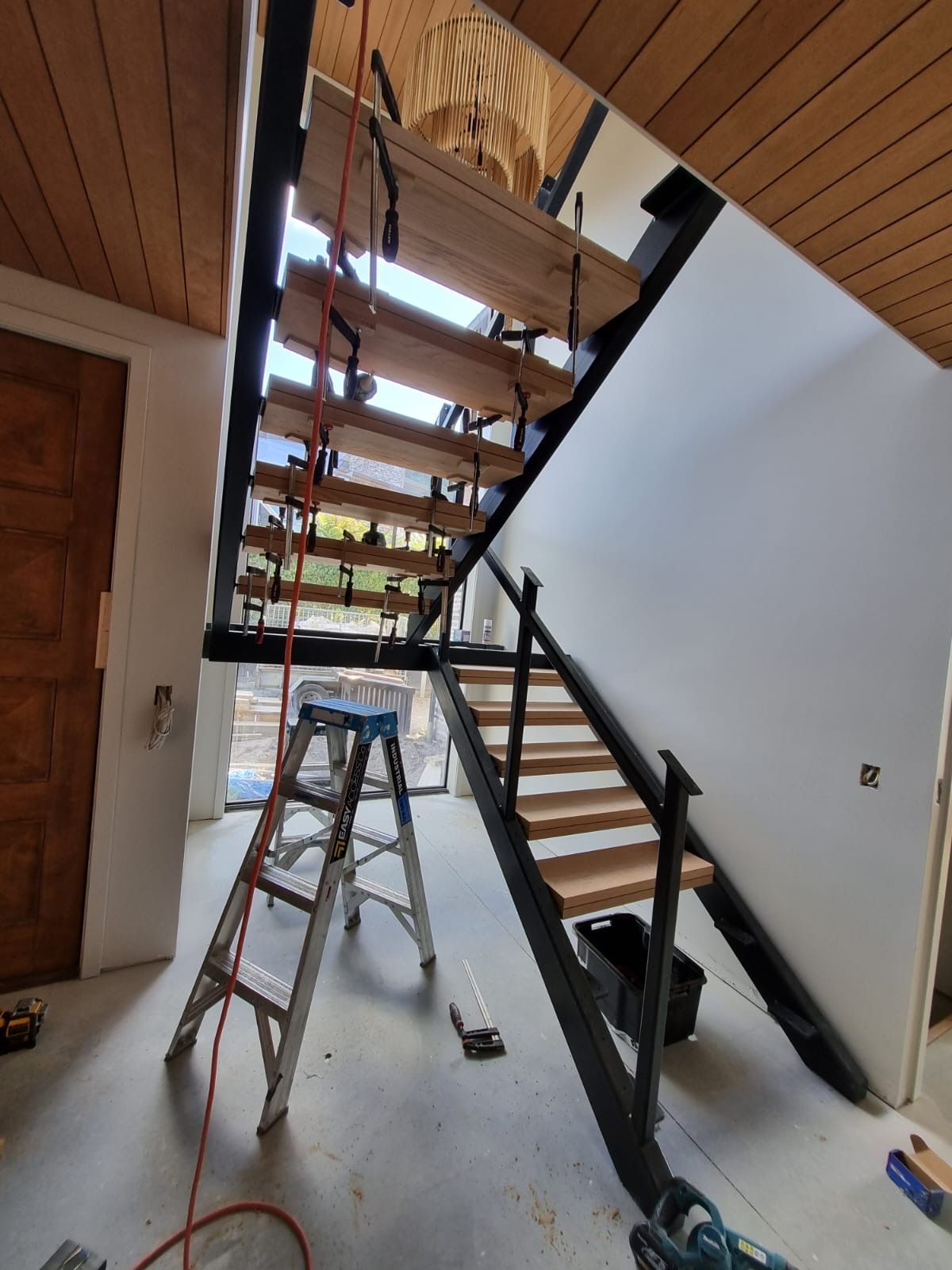 A ladder is sitting next to a wooden staircase in a room.