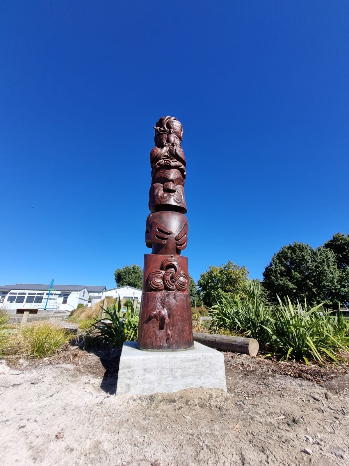 A large wooden statue is sitting on top of a dirt field.